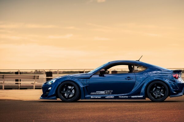 Profile of a blue car at a pink sunset