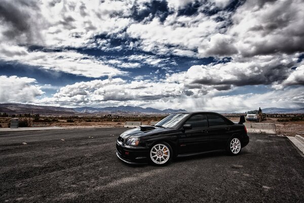 Czarny Subaru na tle białych chmur