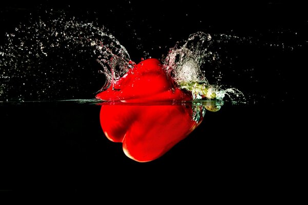 Pepper falls into the water. Red pepper. Beautiful photos of vegetables