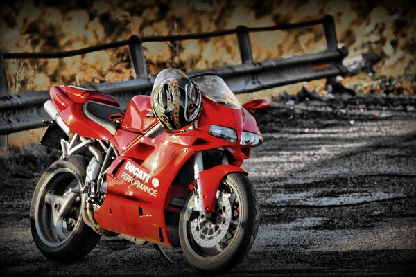 Moto de sport rouge avec casque pesant sur les poignées de gaz