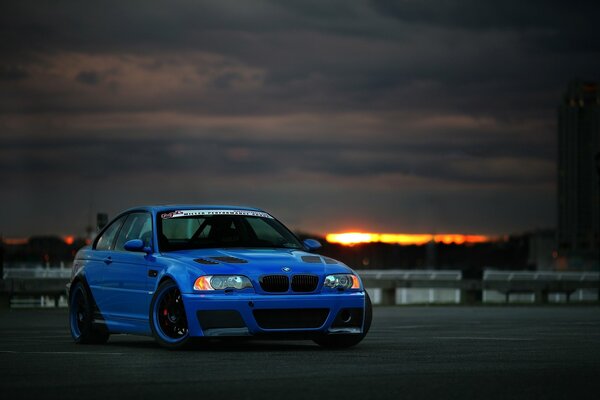 Niebieskie BMW i chmury zachodu Słońca z tyłu