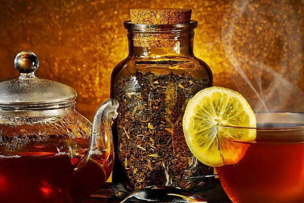 A glass teapot and a cup next to a jar of tea