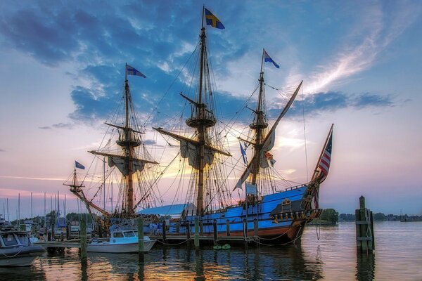 A ship with sails at a small pier