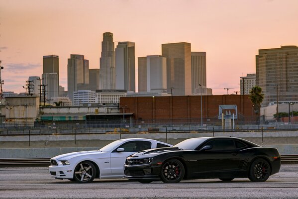 Ford und Mustang fahren bei Sonnenuntergang die Stadtstraße entlang