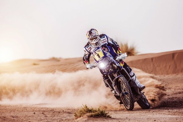 Мотоциклист во время гонок с отлетающим песком