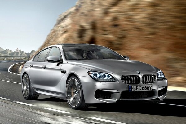 bmw m6 gran coupe car drives at speed over hilly terrain