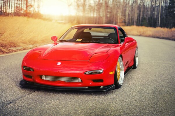 Tuned red Mazda RX-7 on the track in the sun