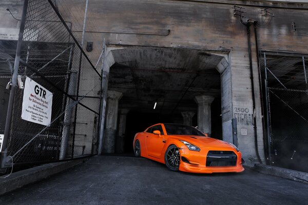 Orange Nissan on the background of a black building opening