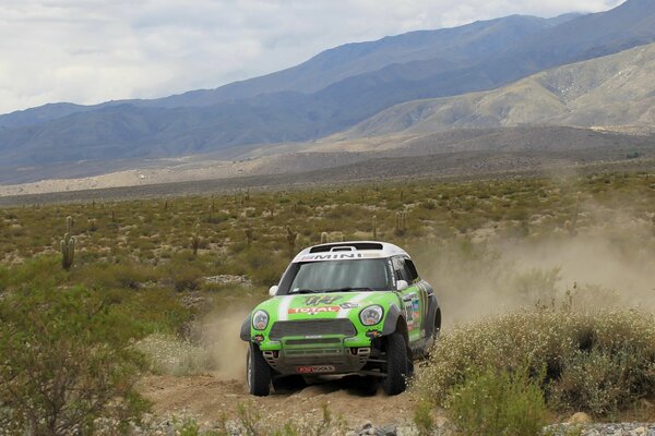 Mini Cooper en el deporte Dakar en el fondo de las montañas