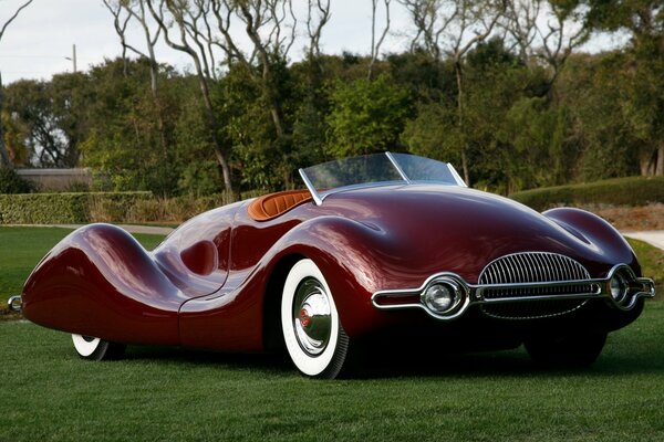 Ретро автомобиль 1949го года Buick streamliner в бордовом цвете, загородное фото