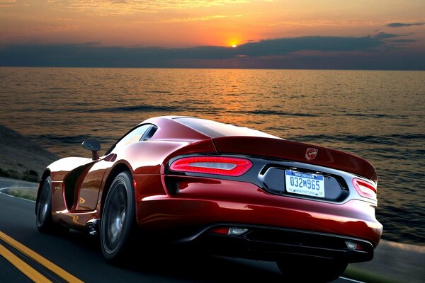 El poderoso Dodge Viper rojo monta en la carretera contra el mar