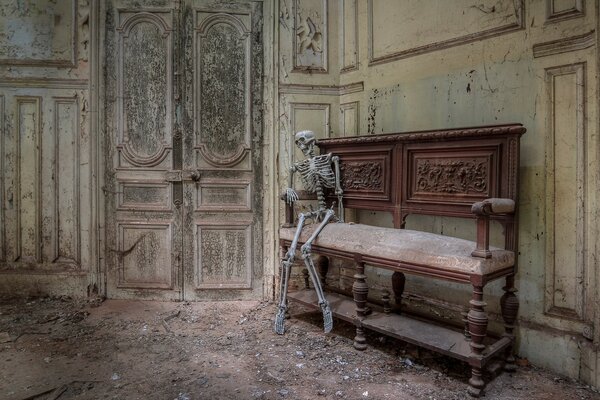 A human skeleton sitting near the door in an abandoned room