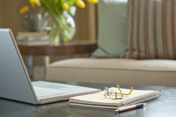 There is a laptop with a notepad and pen on the table