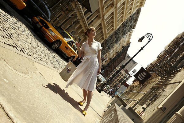 Chica en un vestido blanco en la calle en el fondo de un taxi