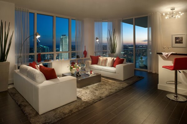 Luxurious living room with white sofas in Miami apartment with a view of the night city