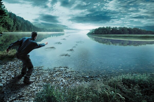 Человек кидает камни в реку у леса