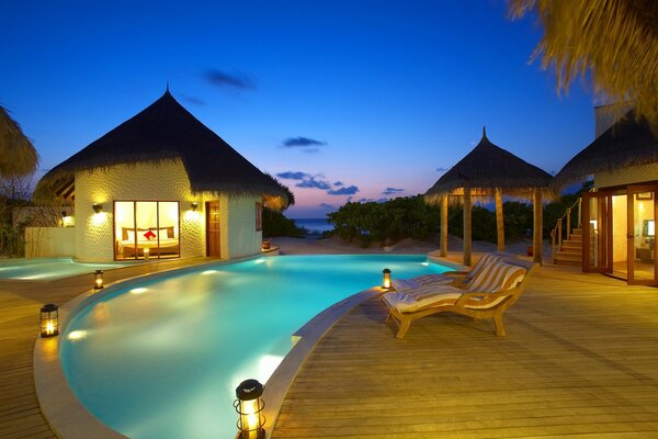 Evening by the pool with lighting and a sunbed