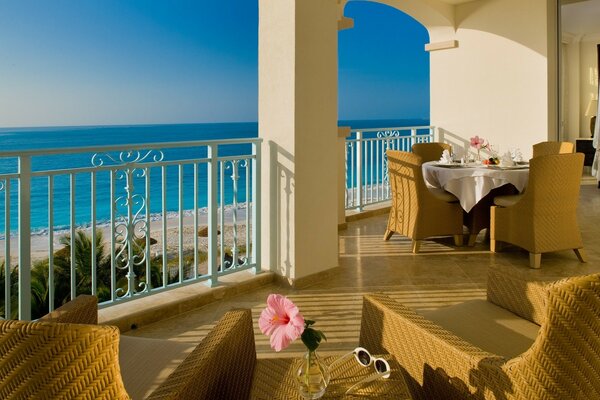 Tavolo apparecchiato e sedie di vimini sulla terrazza con vista sul mare blu