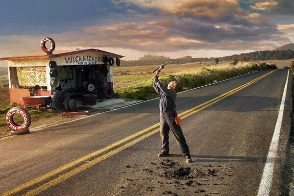 A man in the middle of the road near a tire shop