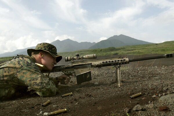 A sniper in the mountains with a rifle is firing