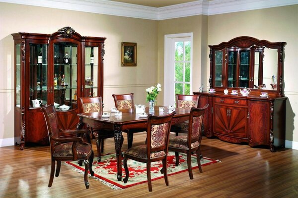 Sala da pranzo in stile classico con mobili intagliati marroni e porta che conduce al giardino