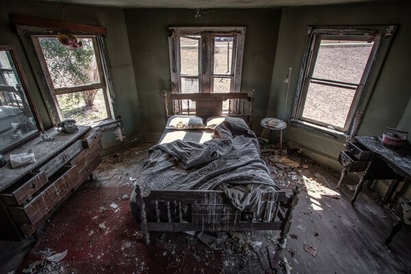 An abandoned room with a bed and other furniture