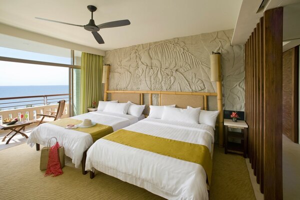 Diseño de la habitación, cama con ropa de cama blanca y verde, mar fuera de la ventana