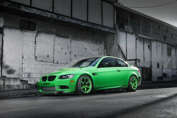 A green BMW is parked at an abandoned building