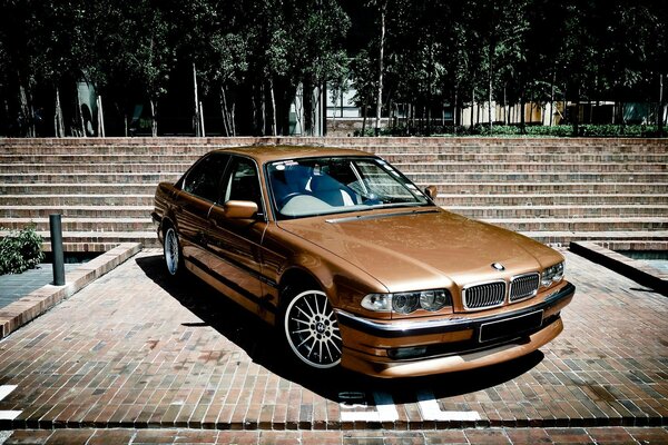 Golden bmw 740 e38 in the city park