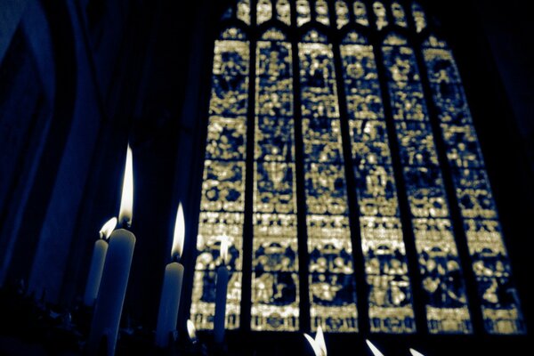 Imagen oscura de velas en la iglesia, grandes vidrieras