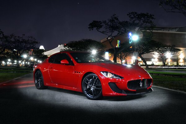Maserati rouge dans la rue à la lumière de la nuit