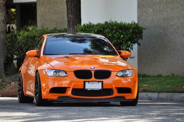 An orange BMW is parked on the street