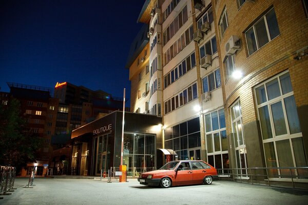 Lada roja estacionada en un edificio de gran altura