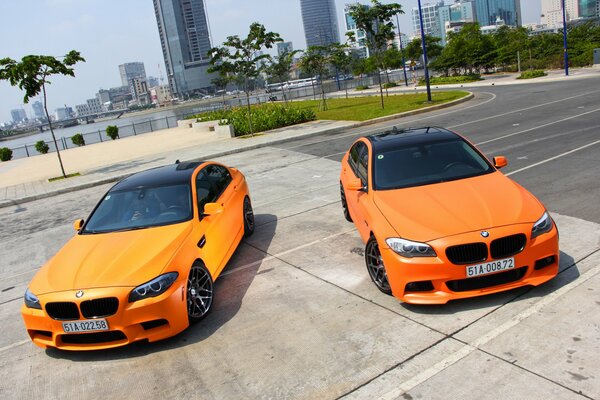 Bmw m5 orange matte on the background of the city