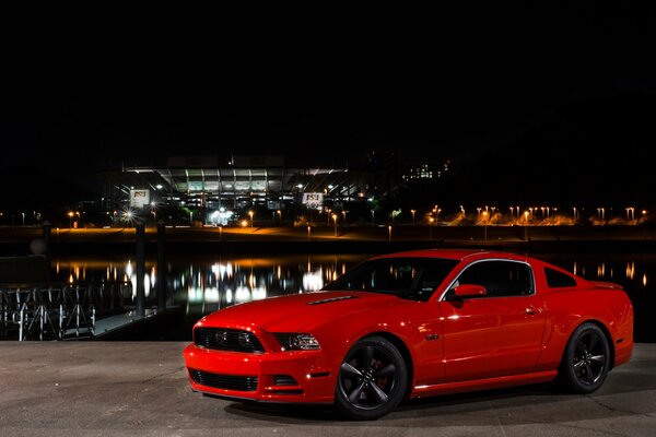 Czerwony Ford Mustang i światła nocnego miasta