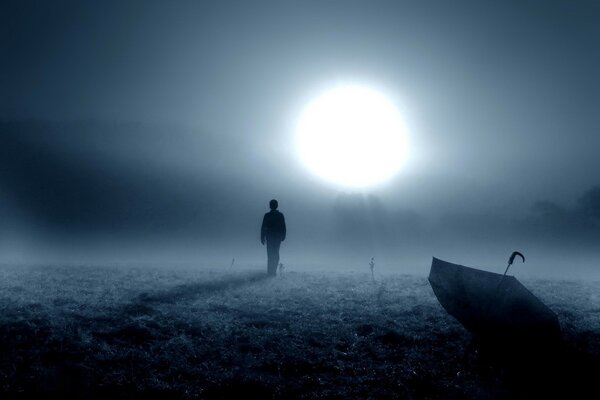 A dark image of a man with an umbrella, a bright ray of light in the dark