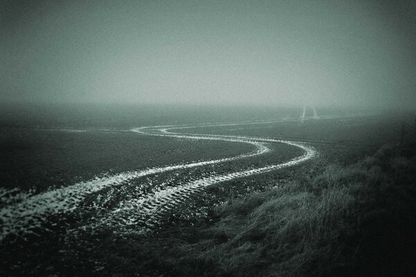 In autumn there is a foggy road in the field