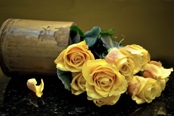 Bouquet di rose gialle in un vaso caduto