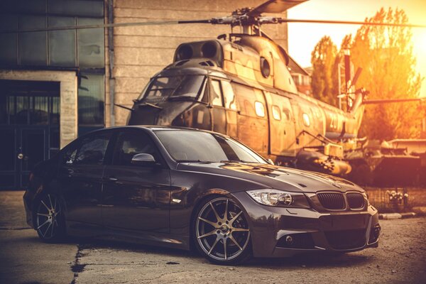 Wallpaper with a black bmw on the background of a military helicopter