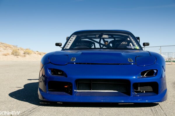 Wallpaper with a blue mazda rx- 7 on the background of a sand quarry