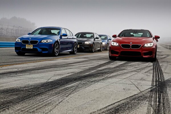 Several BMW cars are driving along the drift highway