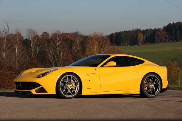 Ferrari amarillo en el fondo del paisaje de otoño