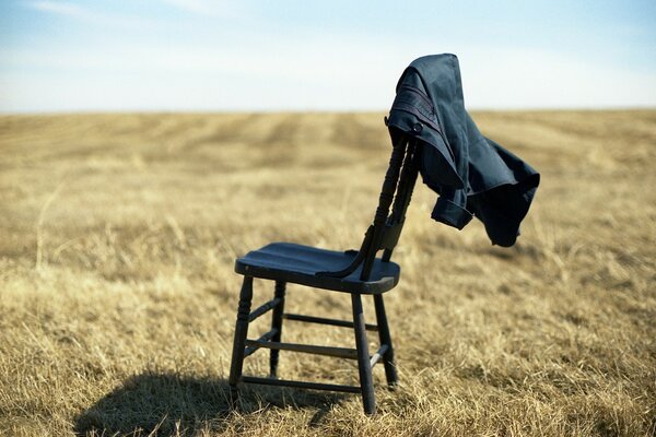 A chair with a jacket on a field background