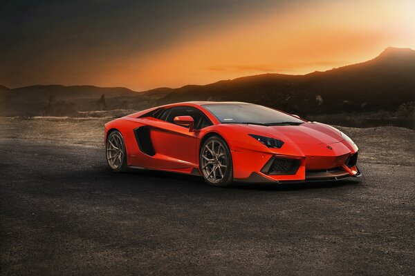 Voiture rouge sur fond de montagnes au coucher du soleil