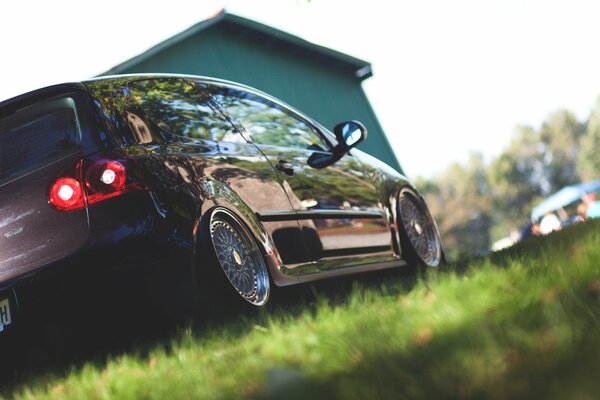 Черный блестящий автомобиль на газоне