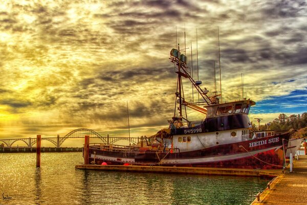 En la pintura paisaje barco en el muelle en la puesta del sol