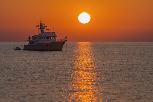 Un barco navega al atardecer por el mar