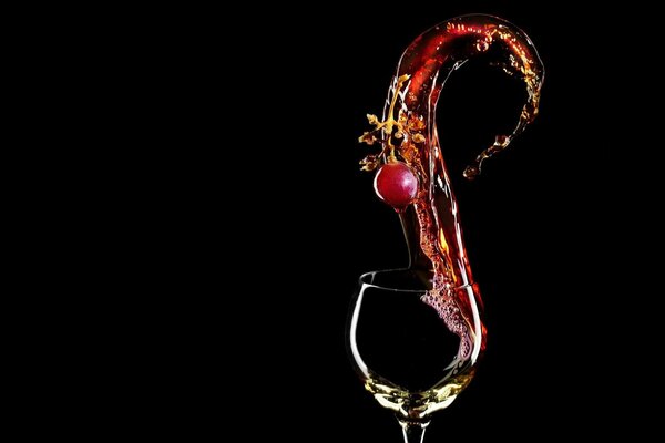 Une cerise tombe dans un verre de vin rouge