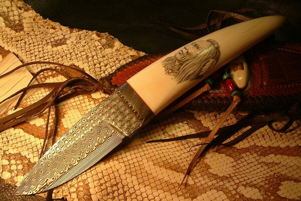 A knife with a bone handle on a snake skin