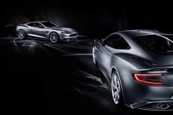 Two aston martin cars on a black background